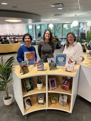 Three librarians stand next to the new World Languages Collection shelf