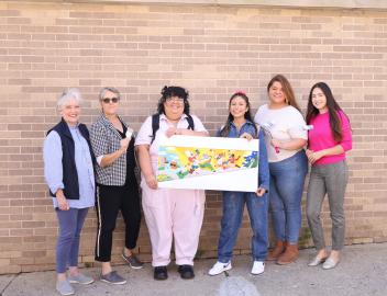 6 people holding a picture of students laughing and jumping outside of the library with books and creativity exploding from their backpacks.